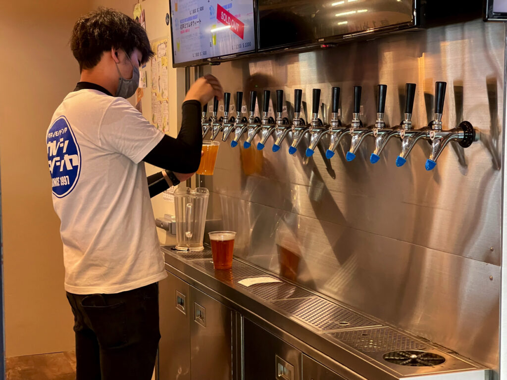 A staff member pouring craft beer from one of many taps in a modern beer bar setup.